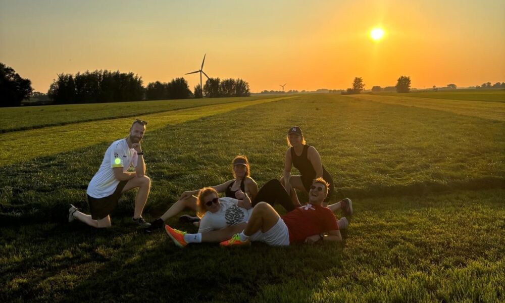 Deel van het team poseert op een weiland bij ondergaande zon.