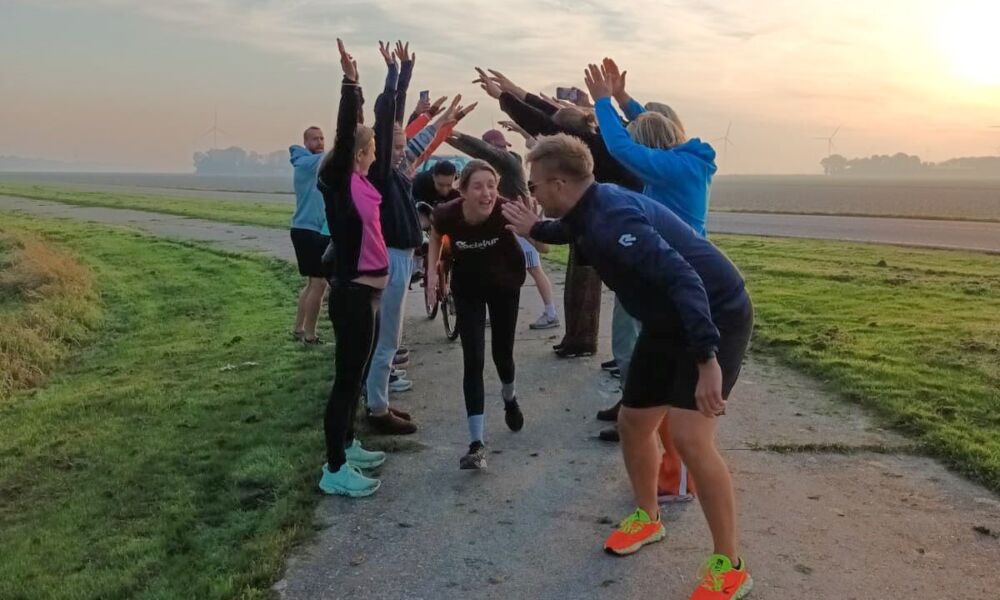 Hardloper rent onder de armen van teamleden heen en geeft high five aan andere hardloper